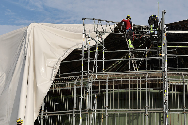 Die Einhausung des Rotundengerüsts wird von Arbeitern entfernt