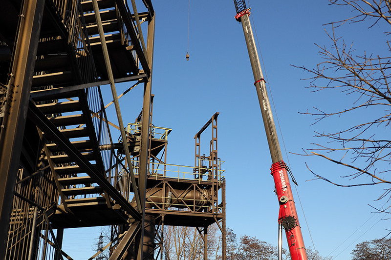 Ein einsatzbereiter Autokran steht an der Rückseite des Gasometers.