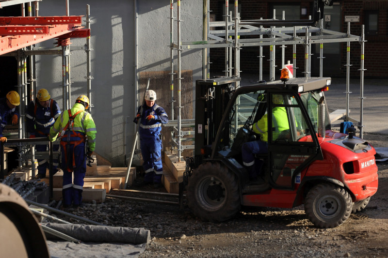 Fünf Gerüstbauer und ein Gabelstabler bei Arbeiten am Gasometer.