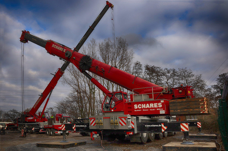 Zwei Autokräne auf stehen der Rückseite des Gasometers.