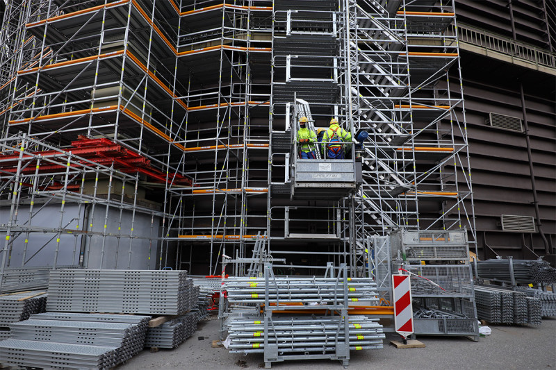 Gerüstbauer transportieren Material für den Gerüstbau am Gasometer mit Hilfe eines Bauaufzugs