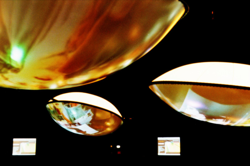 drei gold-weiße Lampen und zwei Bildschirme vor schwarzem Hintergrund