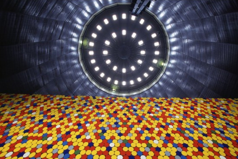 Von unten fotografierte aus bunten Kreisen bestehende Mauer im Inneren des Gasometers mit Blick auf die symmetrisch in zwei Reihen angeordneten Lichter an der Decke.