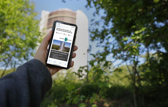 Mobiltelefon mit dem Gasometer-Newsletter auf dem Display. Im Hintergrund ist der Gasometer zu sehen.