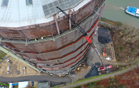 Industriekletterer bei der Demontage der Ausbläser auf dem Dach des Gasometers. Sie werden dabei von einem Kran unterstützt. Gezeigt wird die Vogelperspektive.